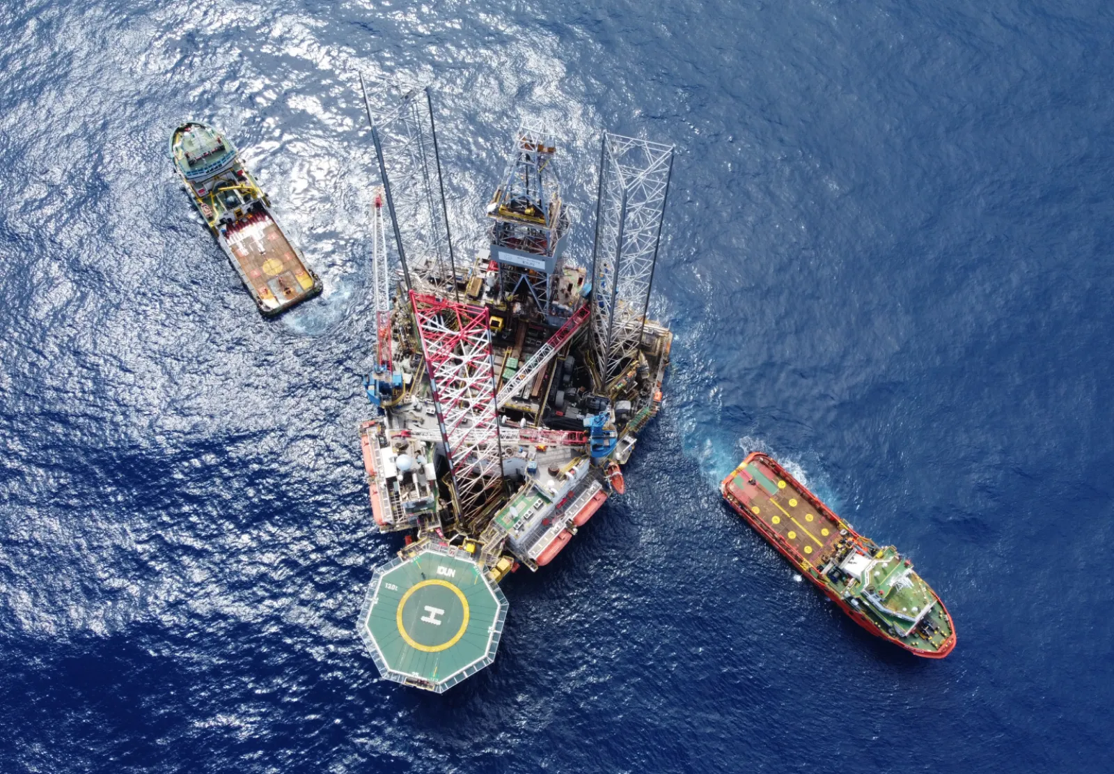 A Borr Drilling jack-up rig seen from above with two support vessels alongside
